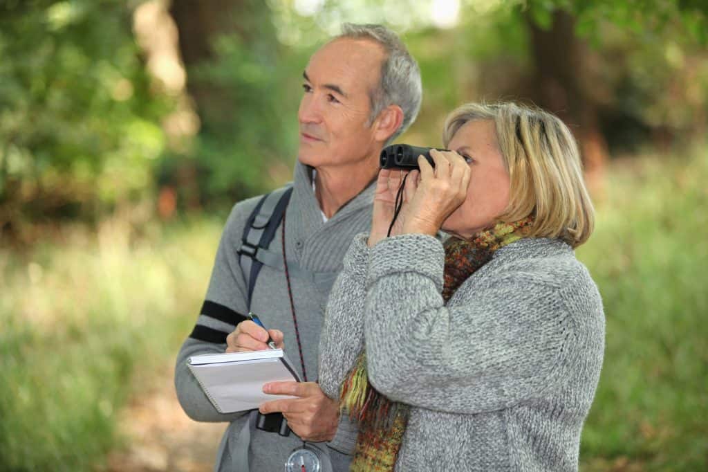 man and woman birding wildlife through meaty binoculars
