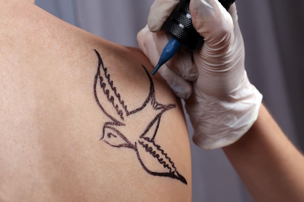 swallow tattoo has meaning and symbolism being drawn on person's shoulder
